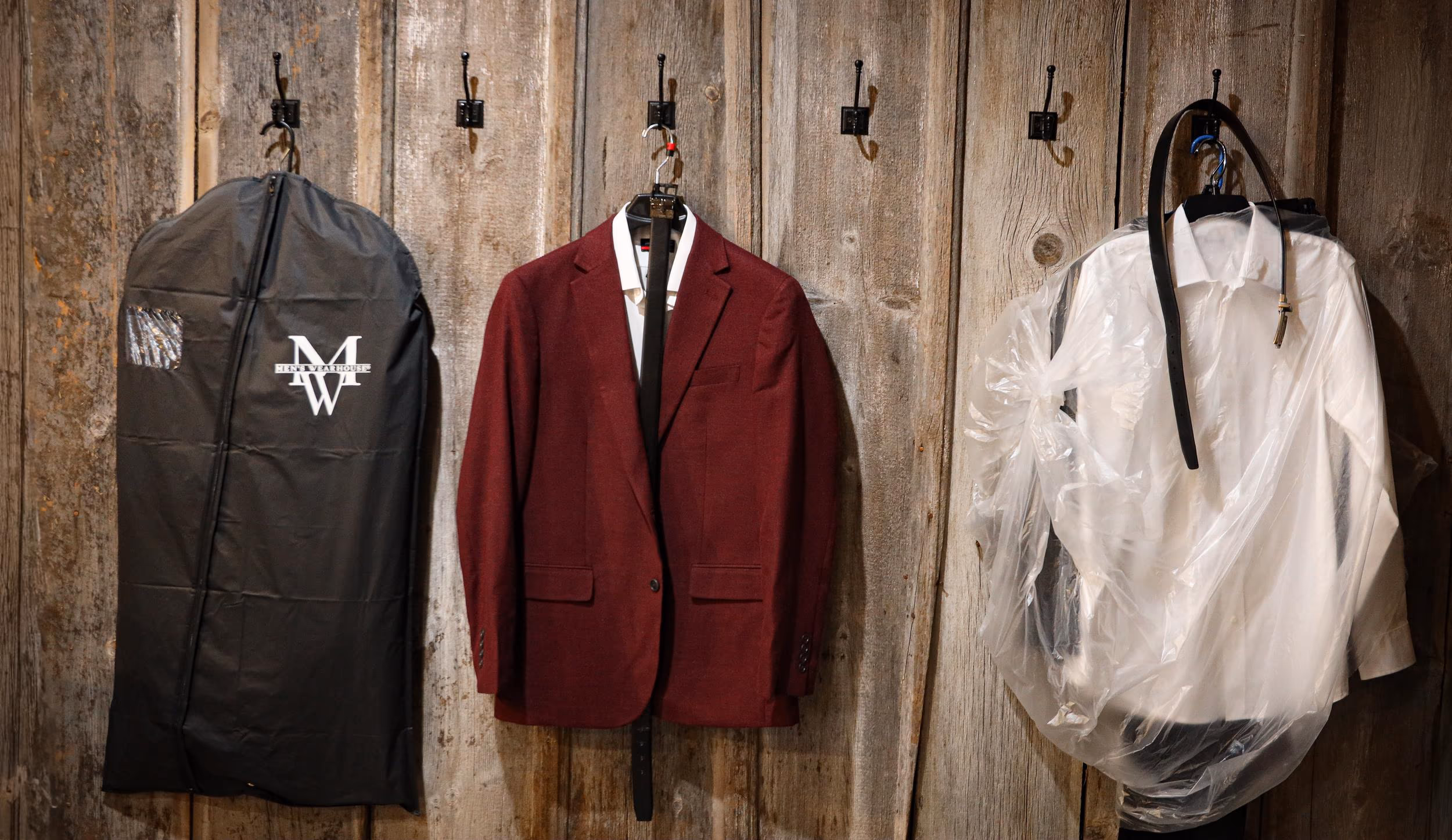 Suits hanging on a barn wall before the ceremony