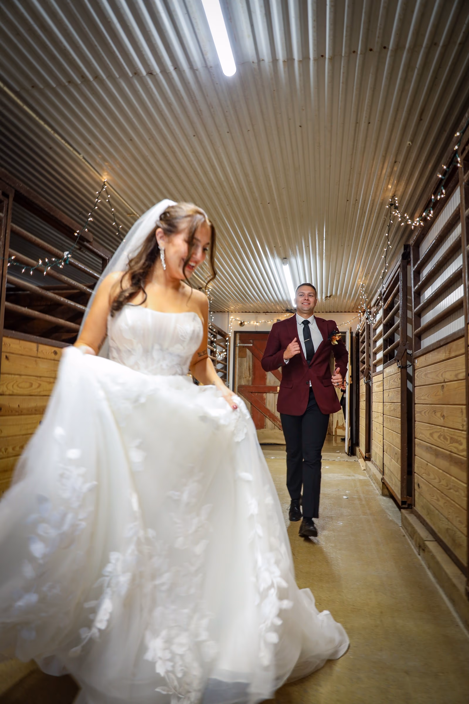 Bride walking through a stable aisle, groom behind her