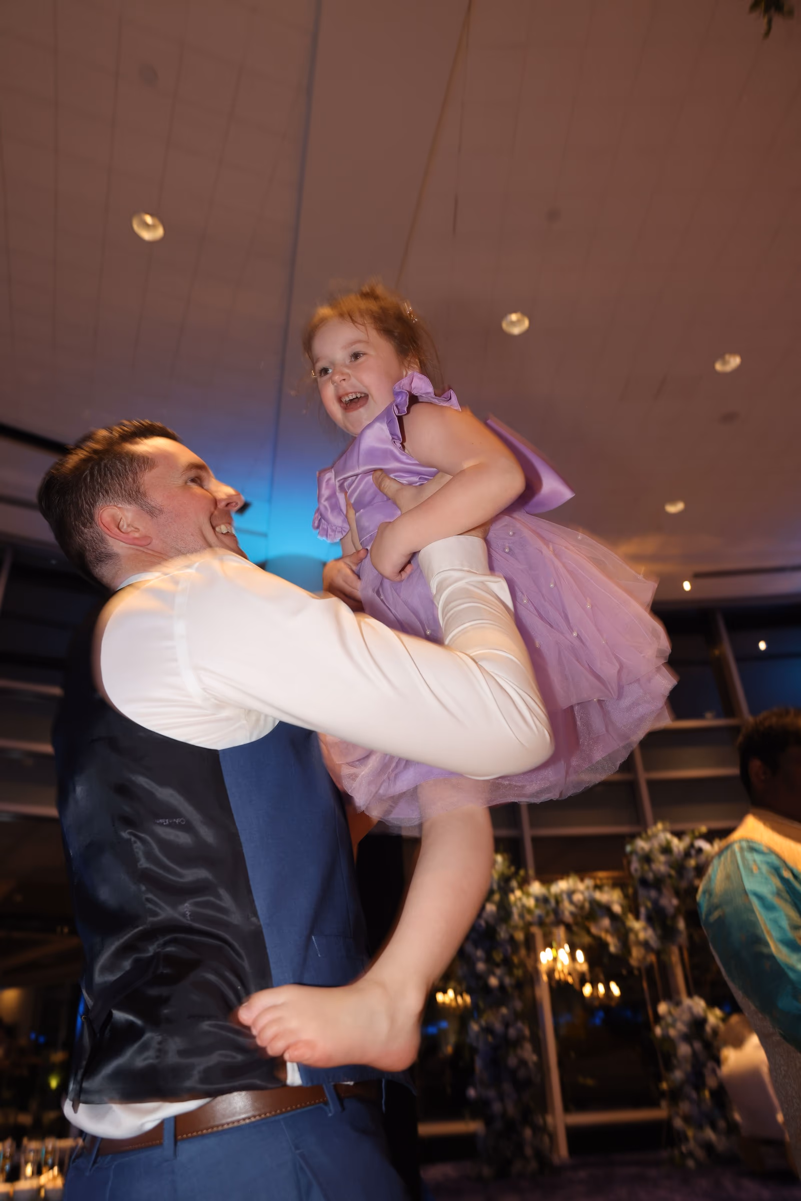 A guest lifting a toddler in a purple dress